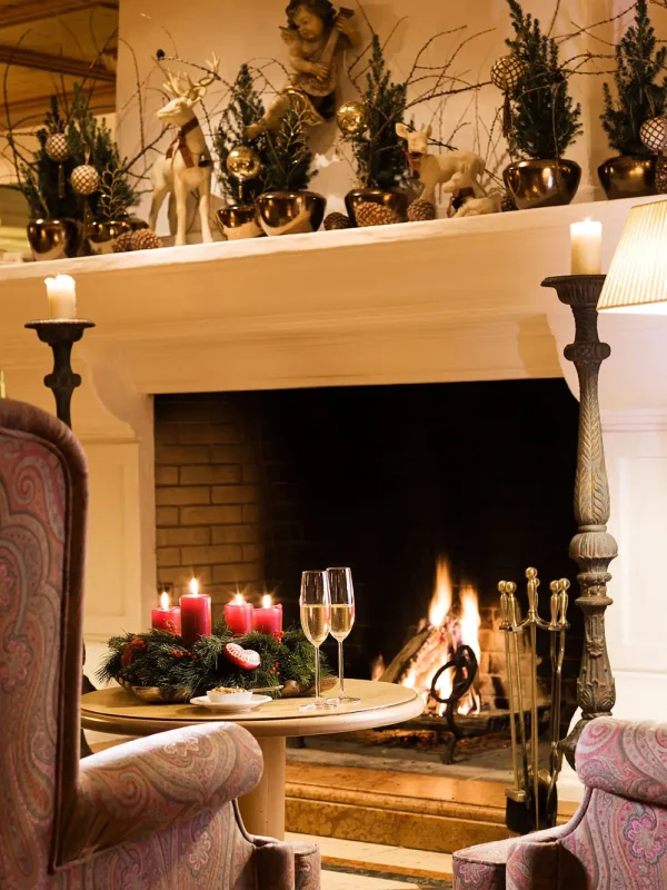 A cozy fireplace with festive Christmas decorations and candles in an elegent lounge setting.